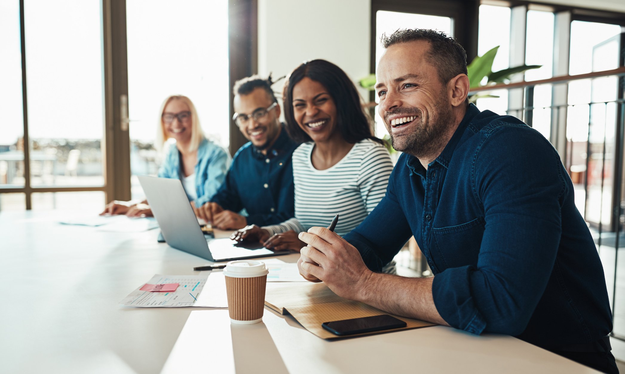 Diverse office colleagues laughing together during a meeting